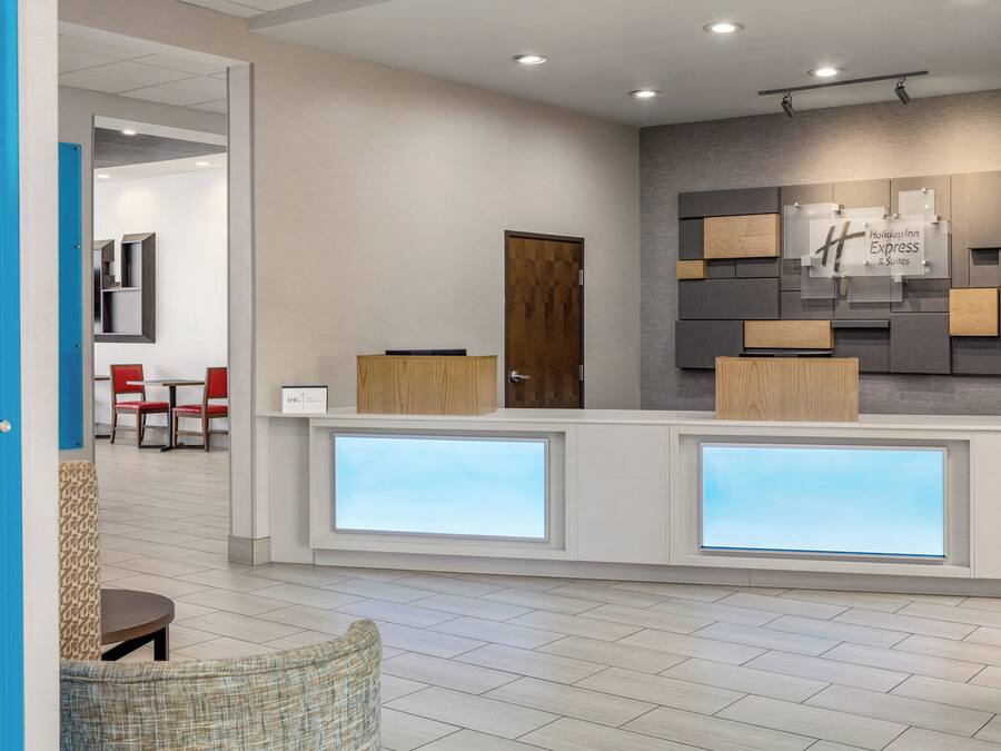 Ein Hotel-Empfangsbereich mit modernem Design, inklusive einer Rezeption, einer Sitzecke und einem an der Wand befestigten Schild.