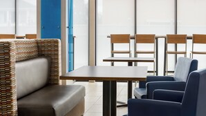 A modern seating area with a patterned bench, a table, and chairs. - Holiday Inn Express Hotel & Suites Waycross by IHG (Waycross)