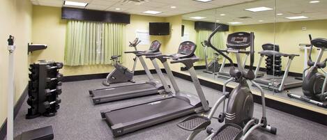 A fitness center with treadmills, elliptical machines, and a weight rack.