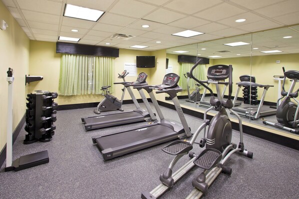 Centre de fitness amb cintes de córrer, el·líptiques i una pilona de peses.