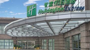 A hotel entrance with a glass canopy and a sign for Holiday Inn Express.