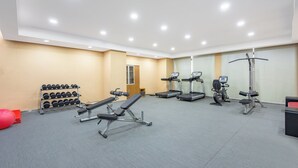 A gym with treadmills, a bench press, dumbbells, and a red exercise ball.