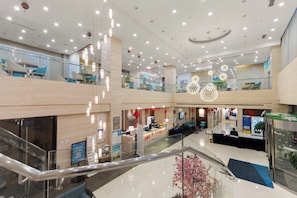 A multi-level hotel lobby with a glass railing, seating areas, and a reception desk. - Holiday Inn Express Suzhou Changjiang by IHG (Suzhou)