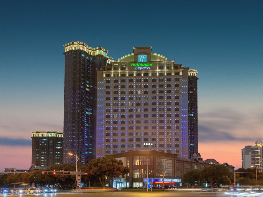 Um edifício alto com um grande letreiro Holiday Inn Express, vários andares e uma ampla área de entrada.