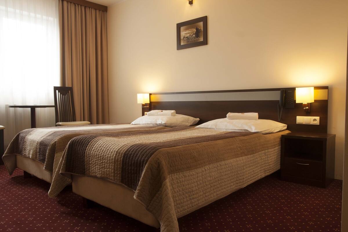 A hotel room with a large bed, two bedside tables, a chair, and a picture on the wall.