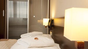 Une chambre d’hôtel avec un lit, une table de chevet, une lampe et une vue sur un balcon.