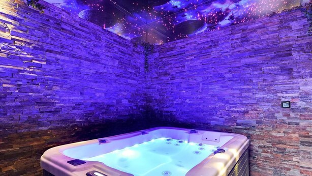 Un bain à remous dans une pièce aux murs de briques et au plafond étoilé.
