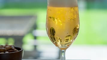 Ein Bierglas wird in ein anderes Glas mit Etikett an einem Tisch mit einer Nuss-Schale daneben gegossen.