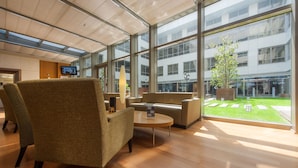 A modern lobby with a large glass wall, comfortable seating, and a small table. - ISG Sabiha Gokcen Airport Hotel - Special Class (Istanbul)