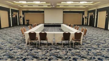 Un salón de conferencias con una larga mesa, sillas y una pantalla para proyector.