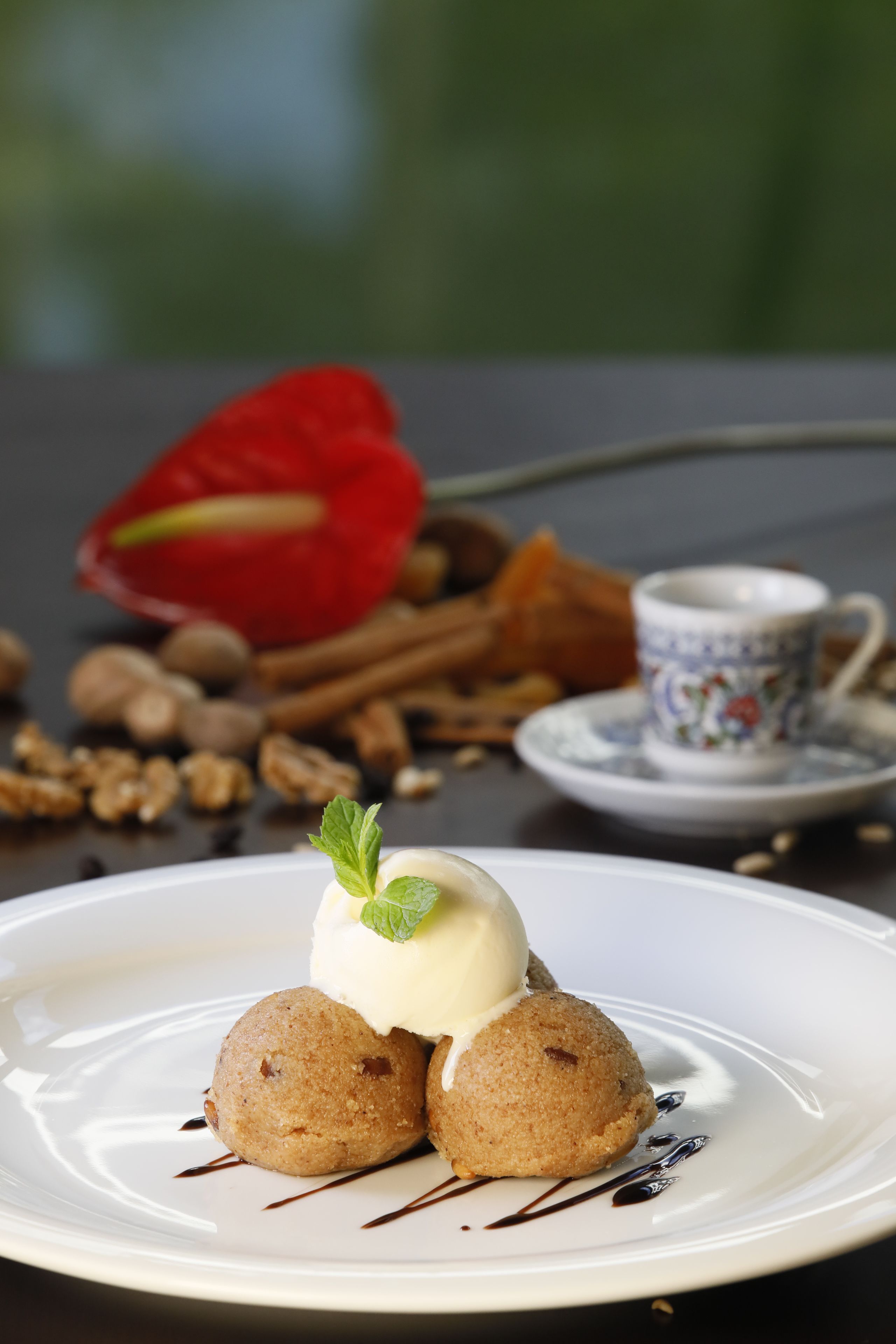 A dessert plate with two round pastries, a scoop of ice cream, and a mint leaf garnish.