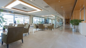 A spacious lobby with modern furniture, a reception desk, and large windows offering views of the outside. - ISG Sabiha Gokcen Airport Hotel - Special Class (Istanbul)