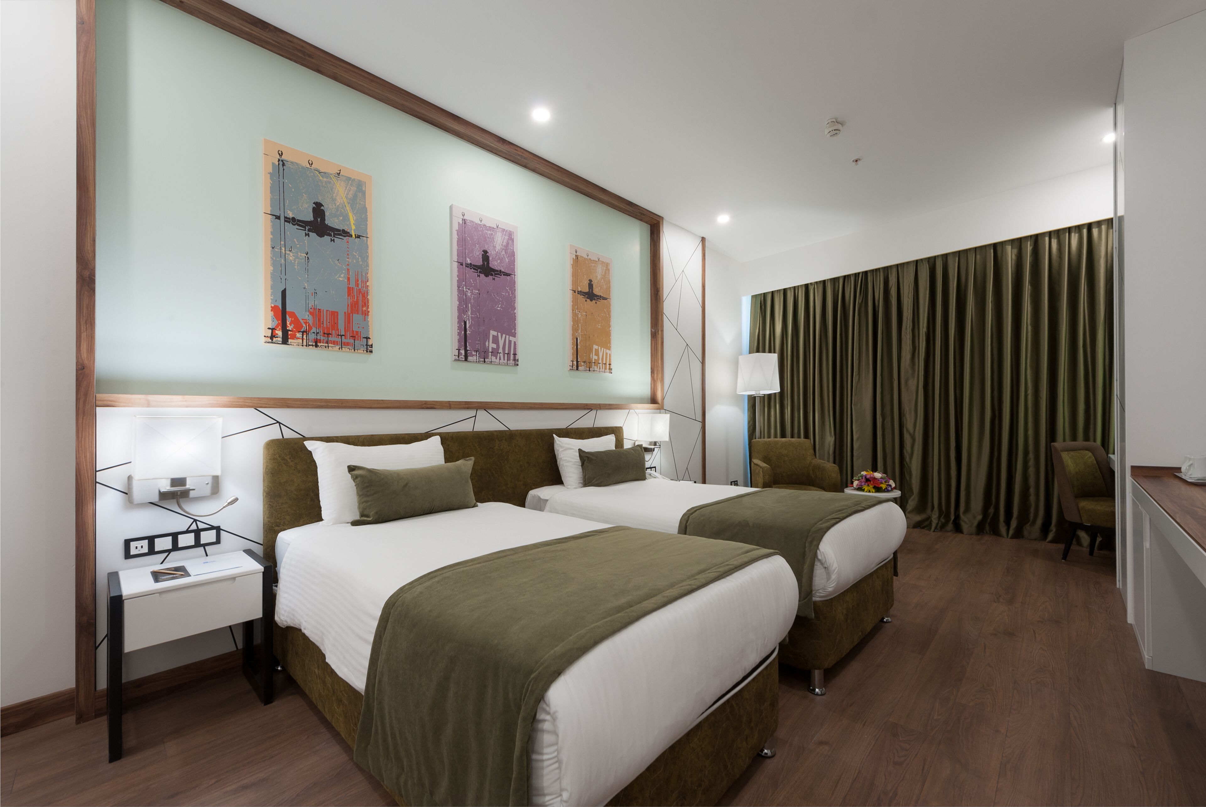 Una habitación de hotel con dos camas, un escritorio, una silla y una cortina.