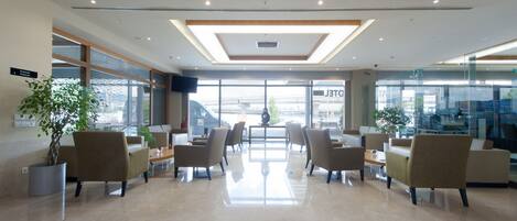 A modern lobby with a central seating area, large windows, and a polished floor.