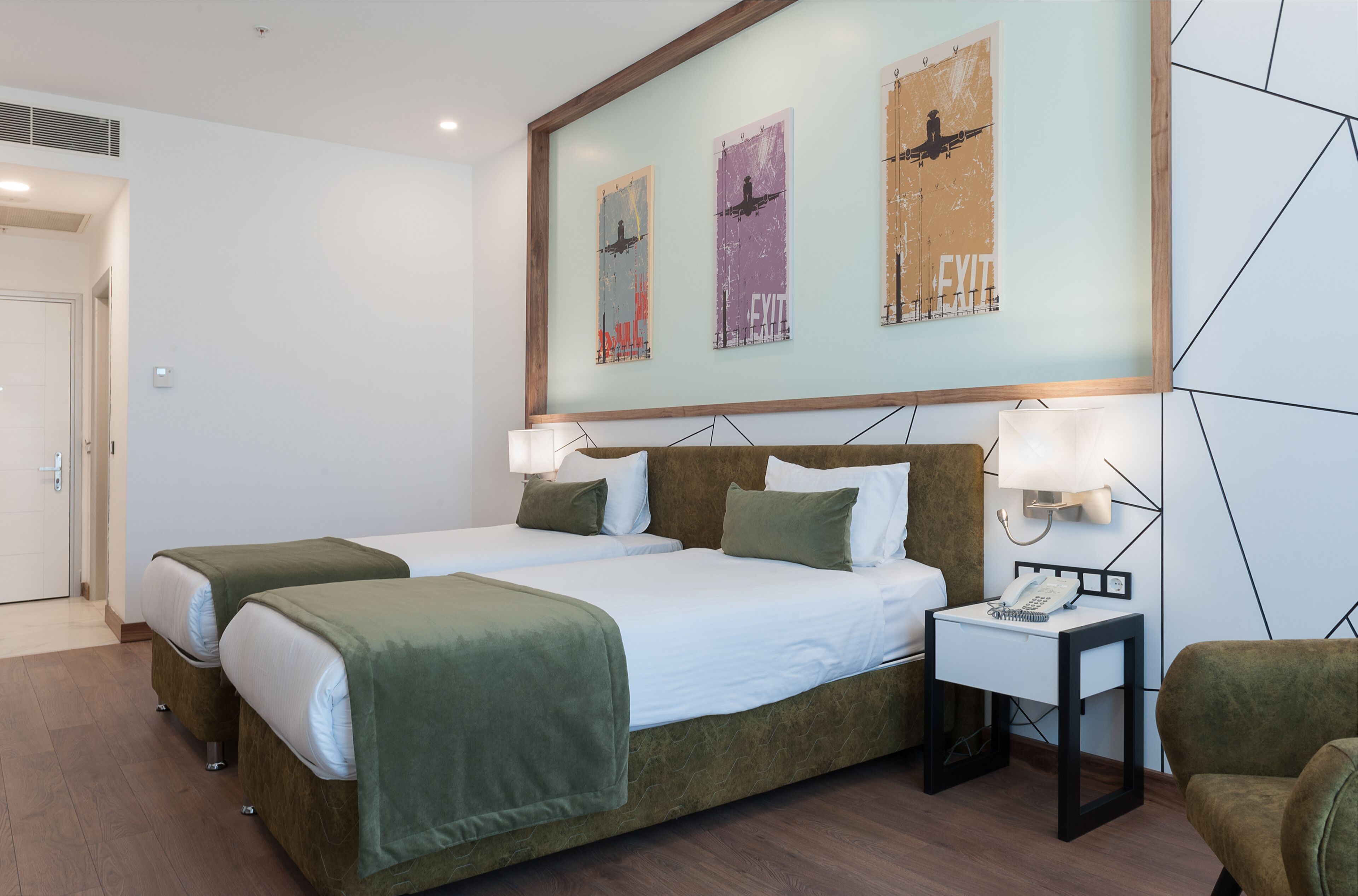Habitación de hotel con dos camas, una mesita de noche con teléfono y una obra de arte en la pared.