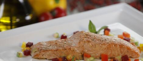 A white plate with a piece of salmon and diced vegetables.