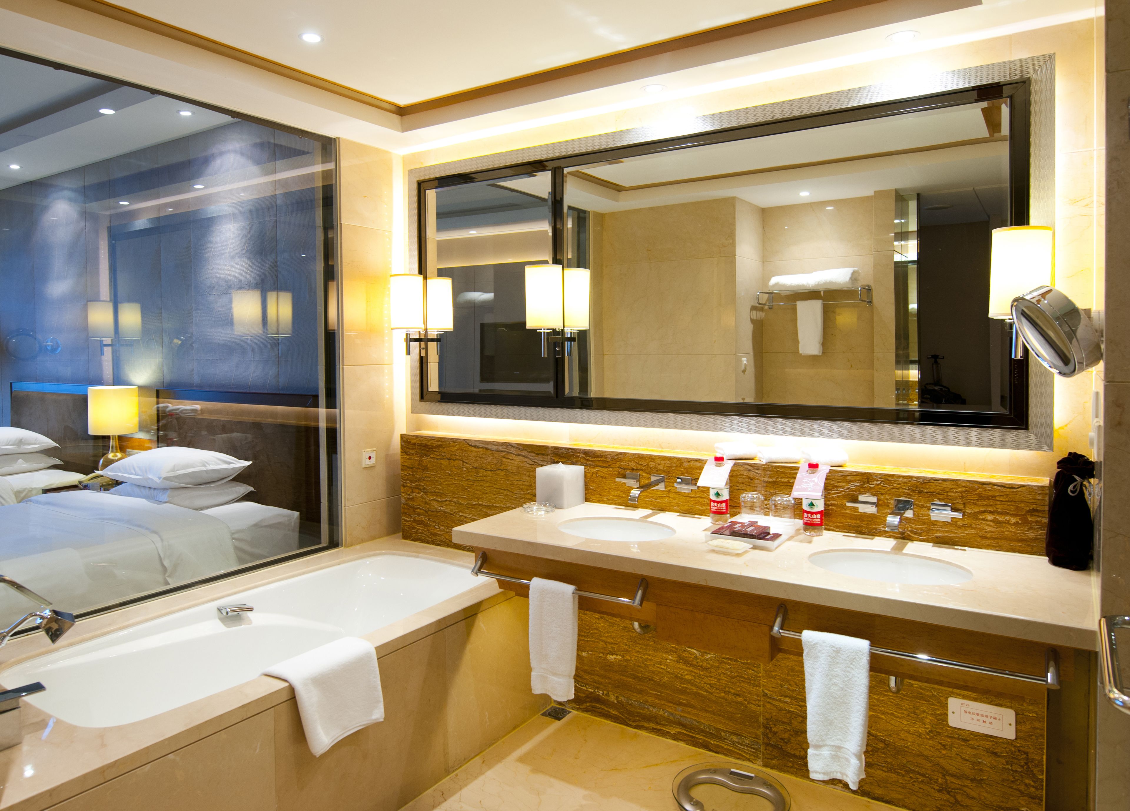 A hotel bathroom with two sinks, a large mirror, and a bathtub.