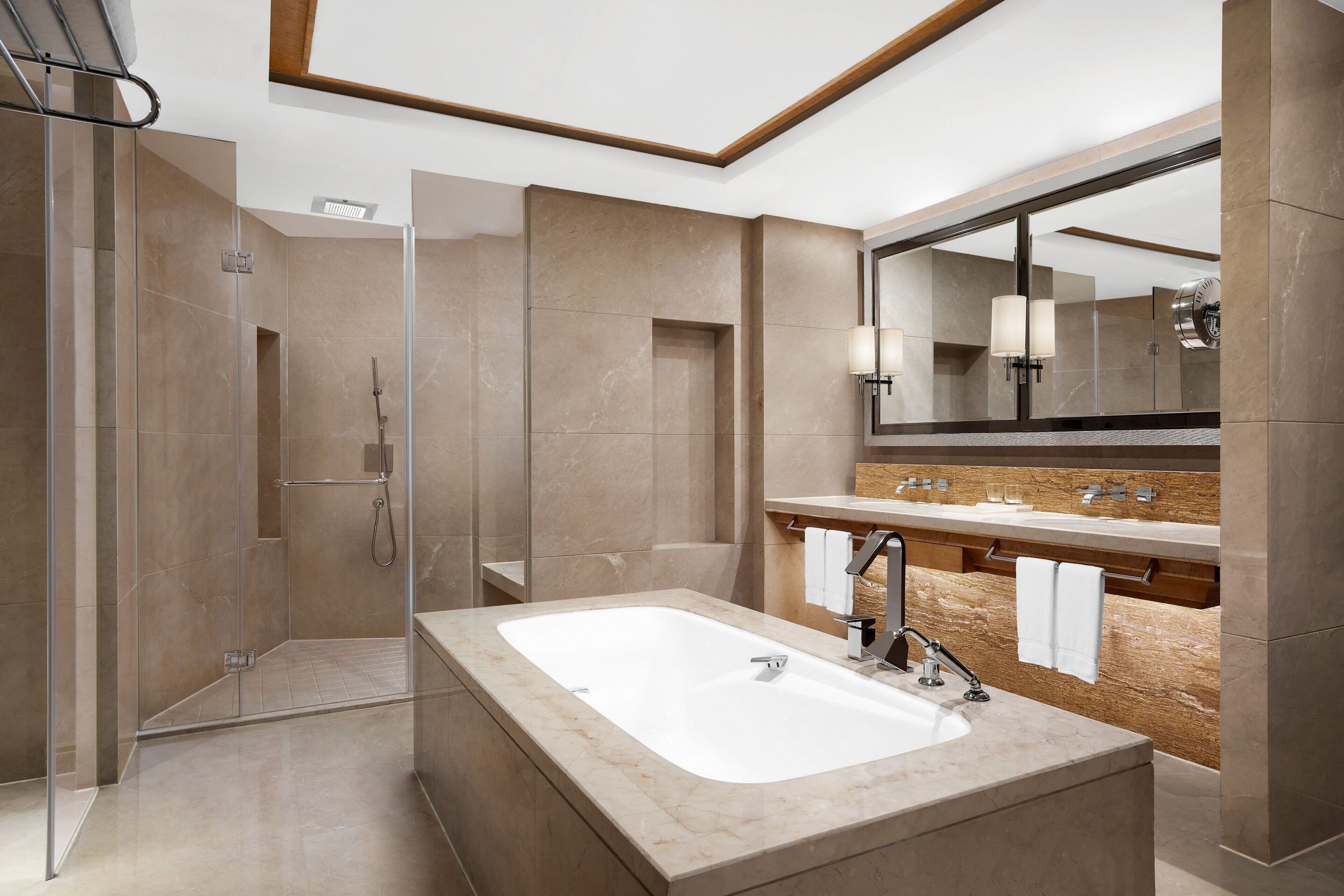 A modern bathroom with a glass-enclosed shower, a large bathtub, and a vanity with a mirror and towel rack.