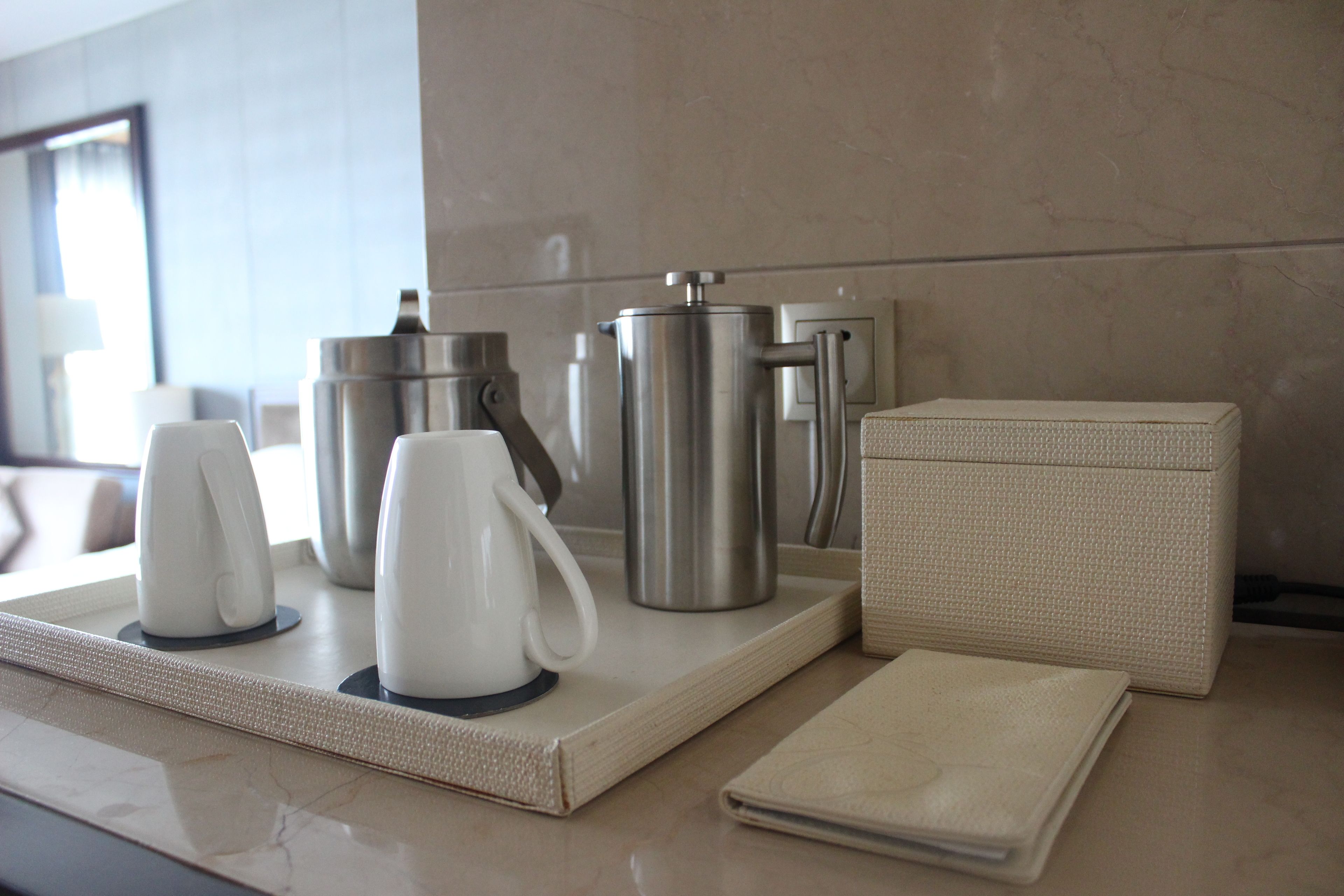 Una encimera de cocina moderna con una cafetera, un hervidor, una termo y un portalapizarras tejido.
