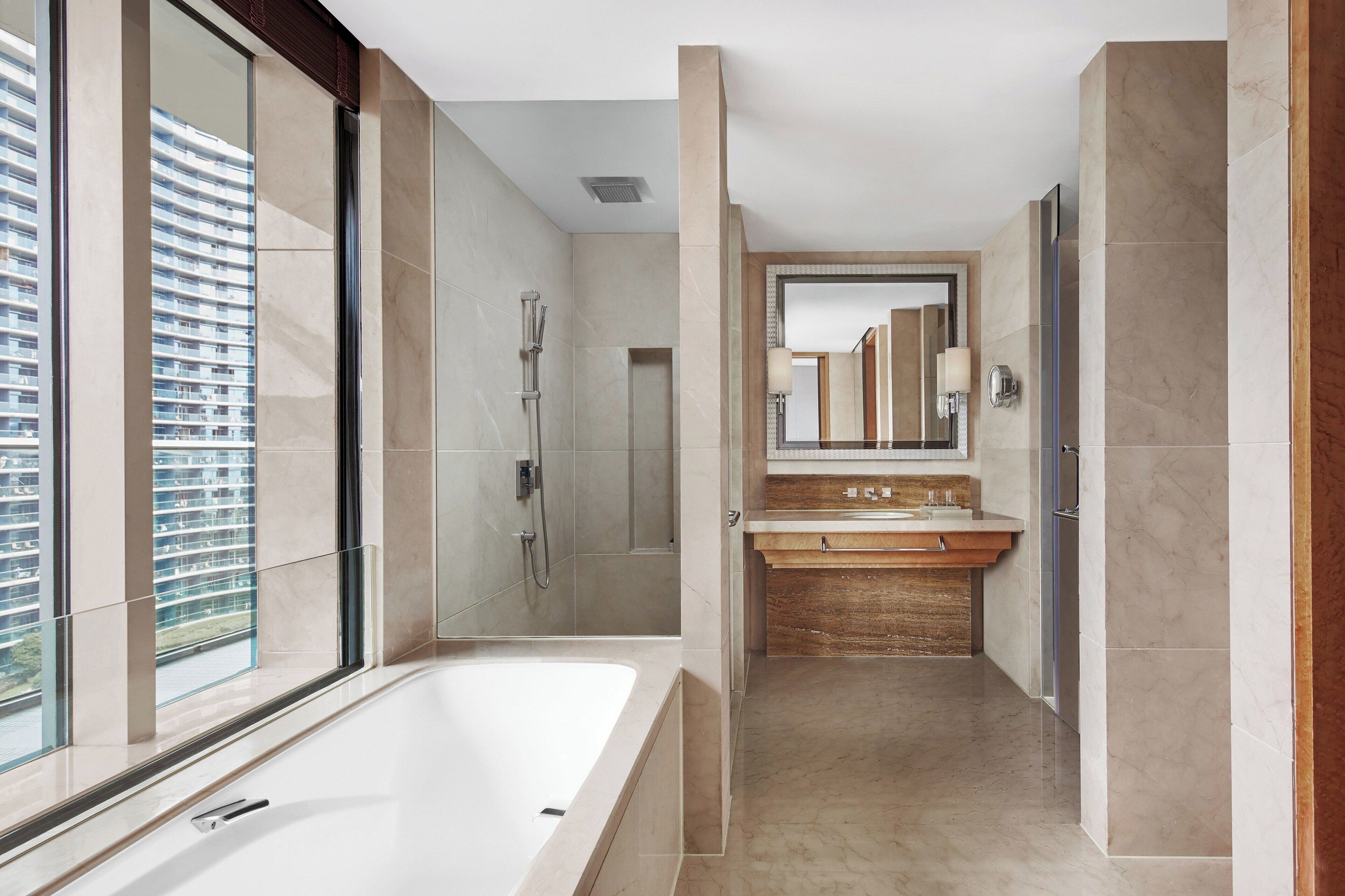 Ein modernes Badezimmer mit einer großen Badewanne, einer gläsernen Dusche und einem Waschtisch mit Spiegel.