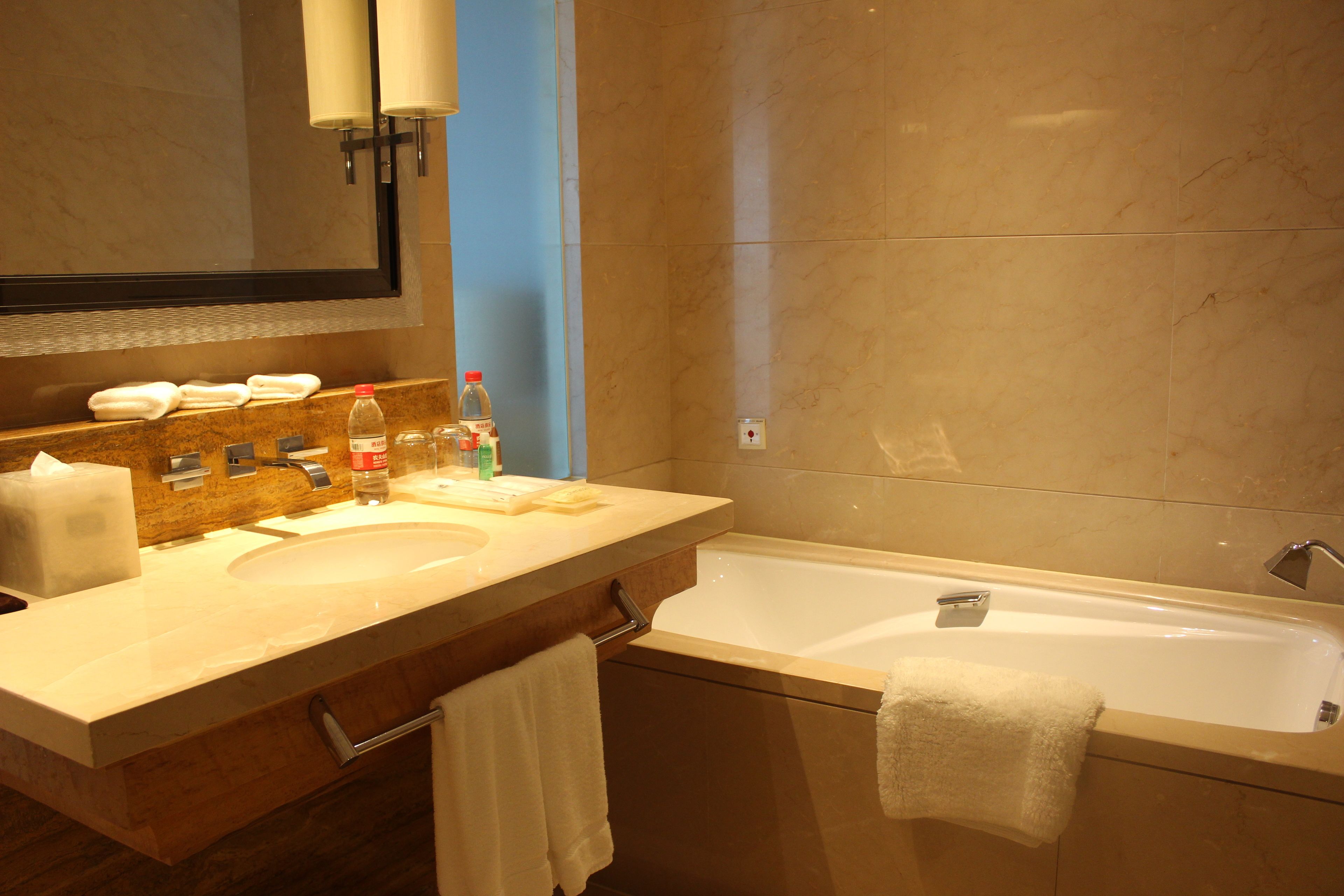 A bathroom with a double sink vanity, a bathtub, and a large mirror.