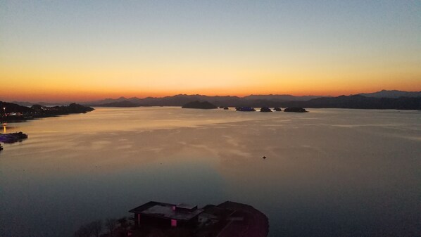 A calm lake at sunset with distant mountains and a few small islands.