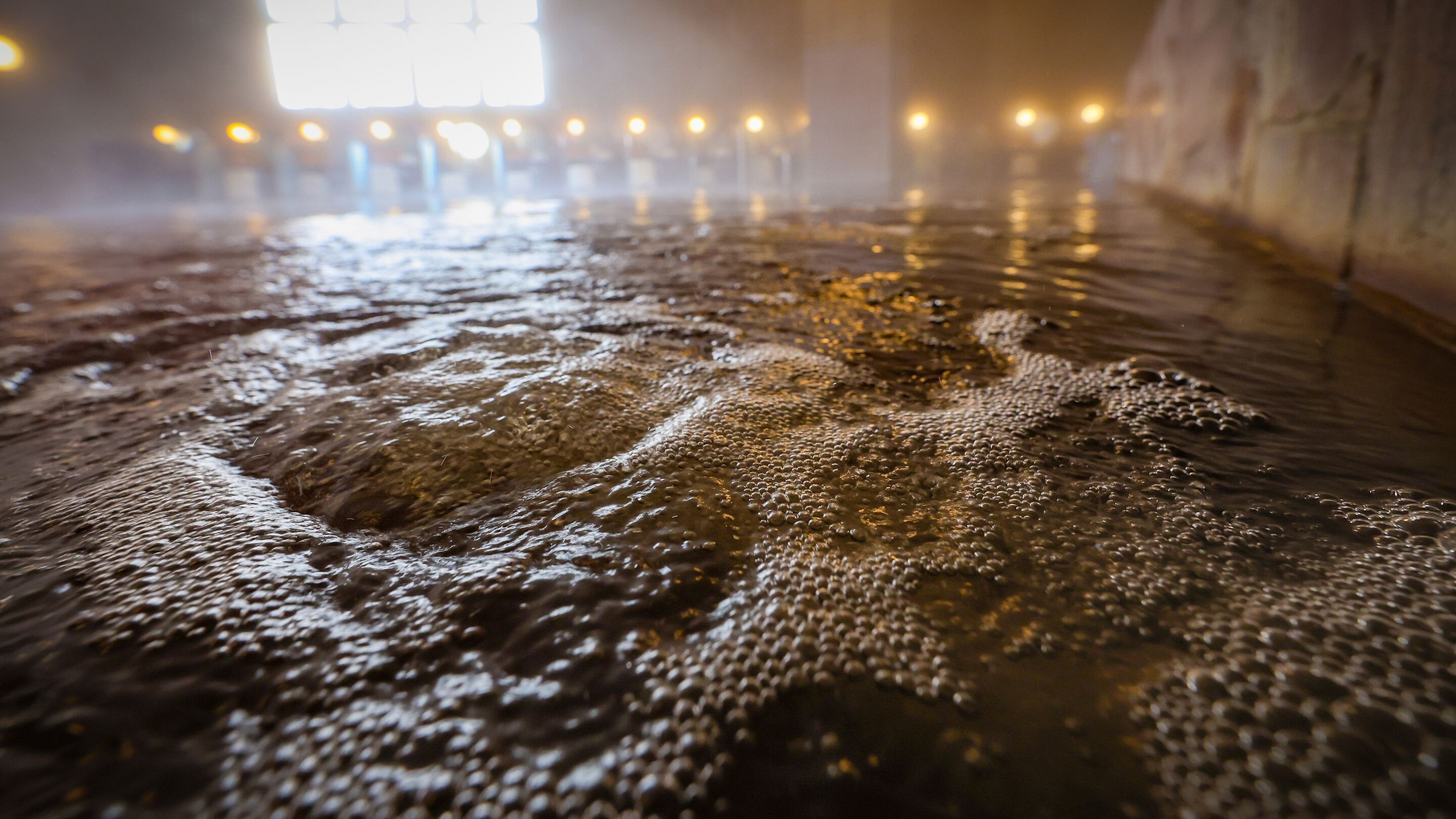 A close-up of a bubbling hot spring with a blurred background of lights.