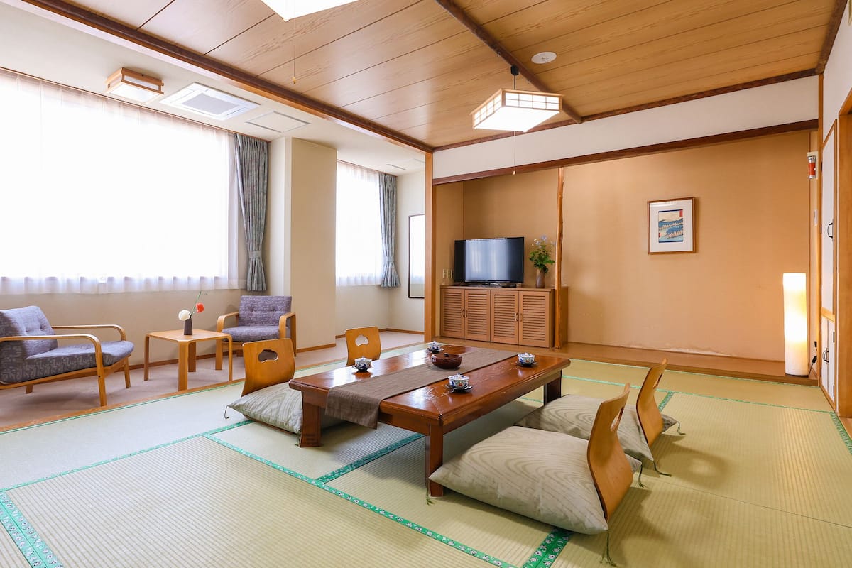 A traditional Japanese-style room with tatami flooring, a low table, and seating arrangements.