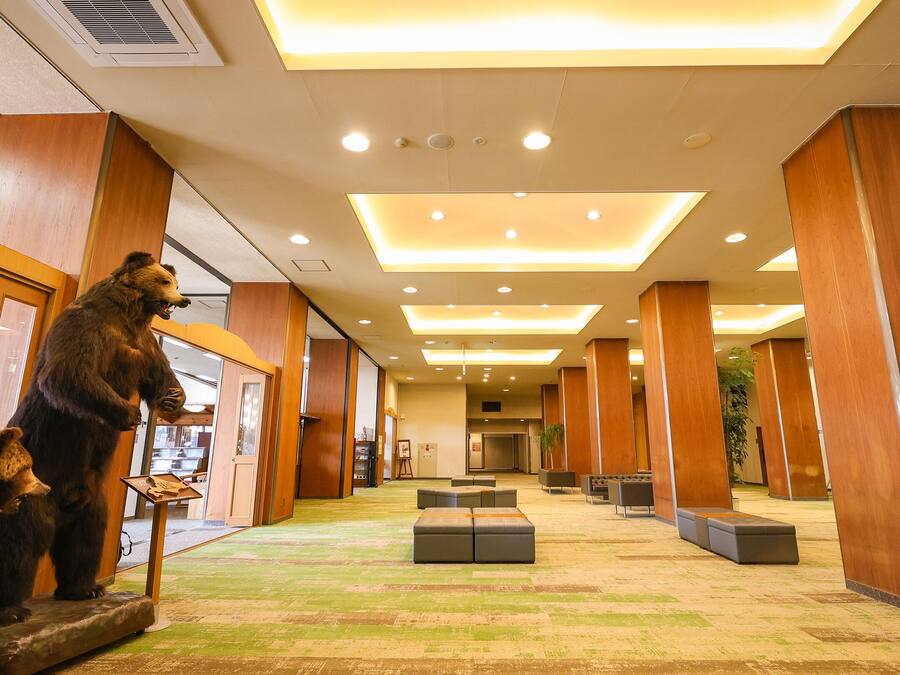 A lobby with wooden pillars, a bear statue, and a green carpet.