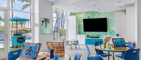 A bright room with large windows, a flat-screen TV, and blue chairs.