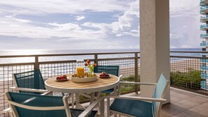 A balcony with a table set for breakfast, overlooking the ocean.
