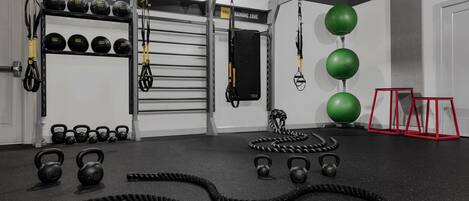 Un gimnasio con correas TRX, pesas de cañón y balones de ejercicio.