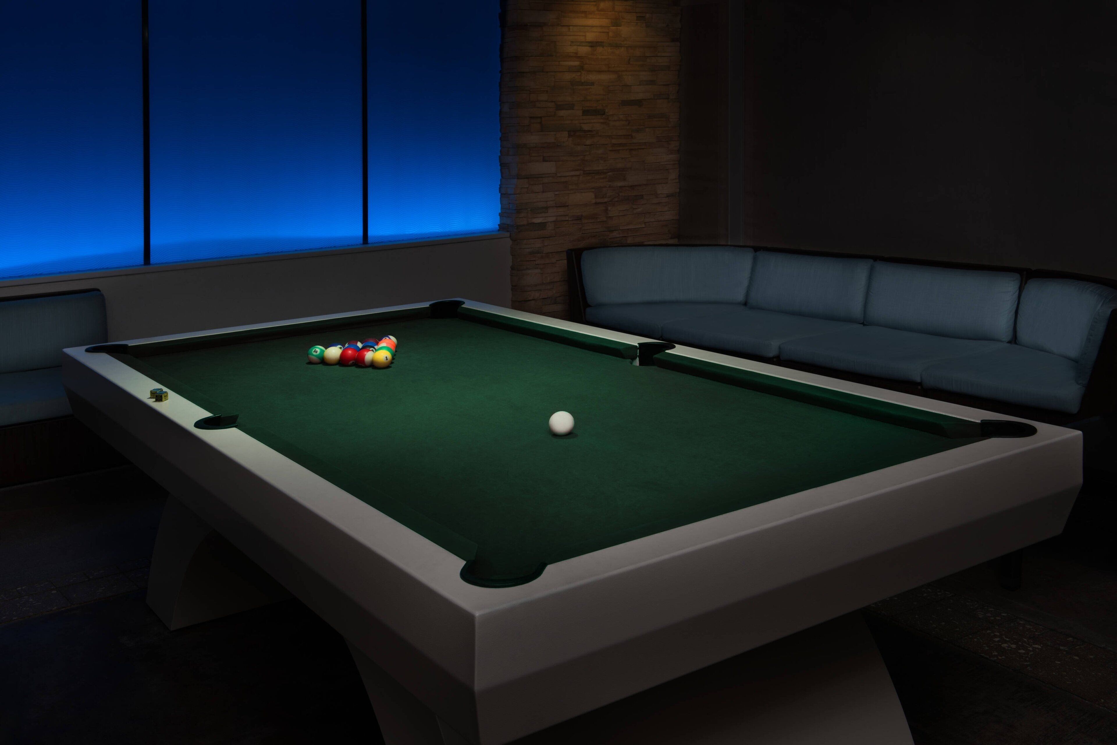 Une table de billard avec des billes, un canapé et un mur en briques.