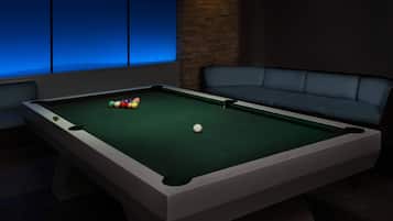 A pool table with balls, a sofa, and a brick wall.