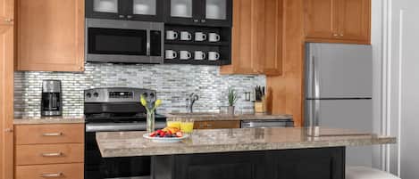 Una cocina moderna con armarios de madera, un refrigerador de acero inoxidable, un microondas y una cafetera.