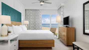 Une chambre d’hôtel avec un grand lit, une télévision, un bureau et une vue sur la plage.
