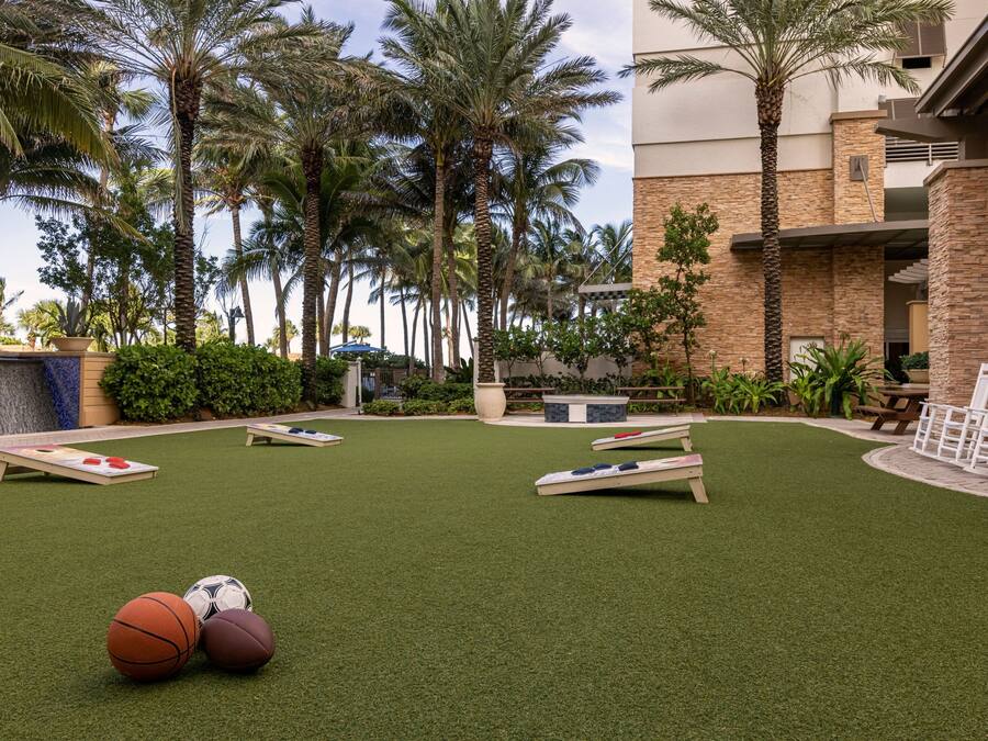 Un espace extérieur doté d’une pelouse artificielle, d’un terrain de basketball et d’une table de billard.