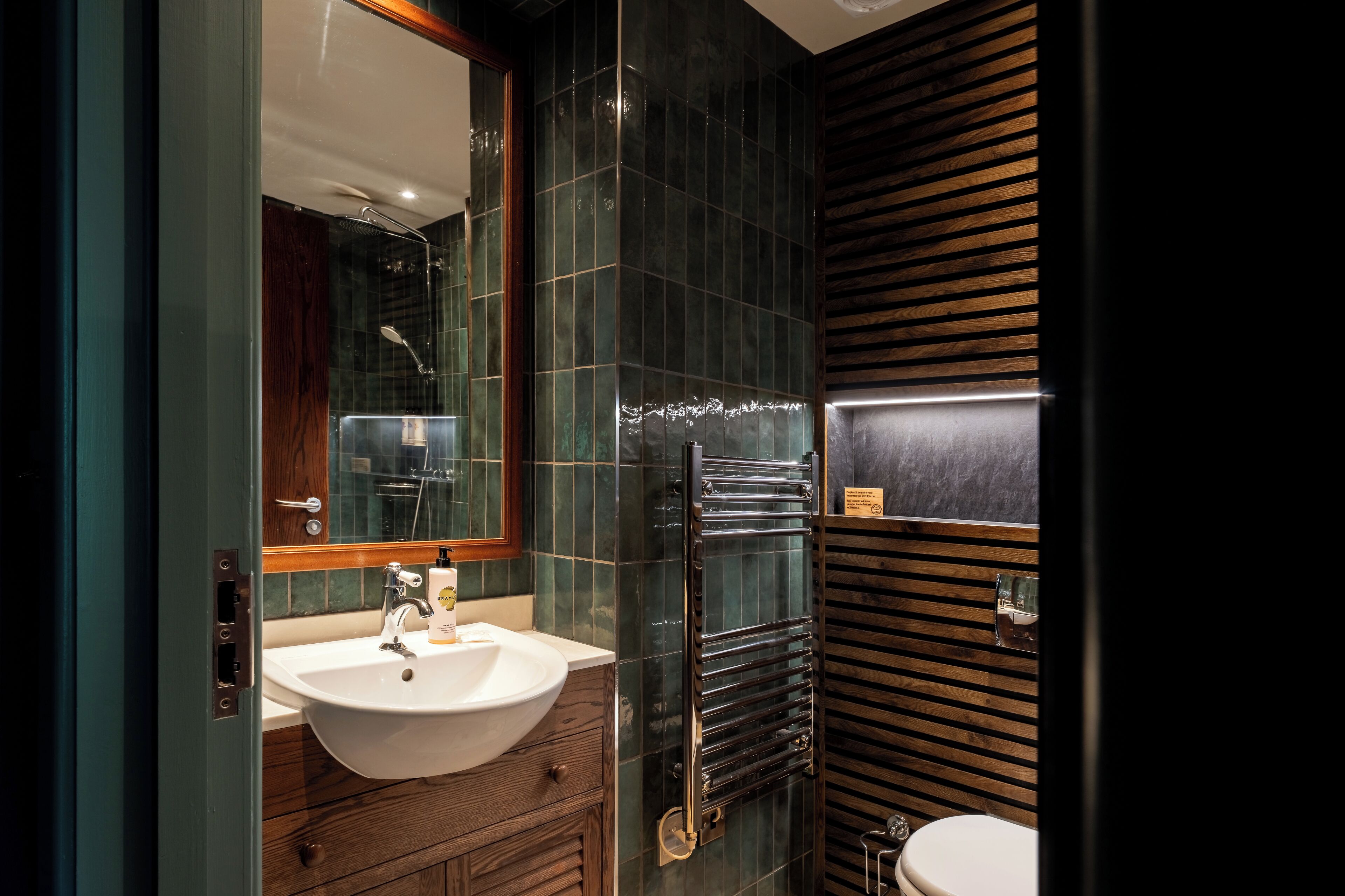 A modern bathroom with a large sink, mirror, and a towel rack.