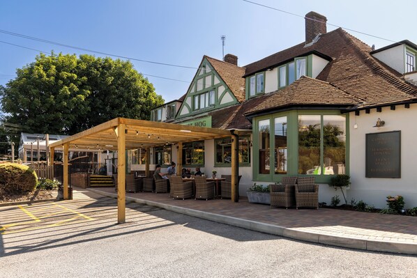 A traditional building with a covered outdoor seating area and a sign indicating it is a pub.