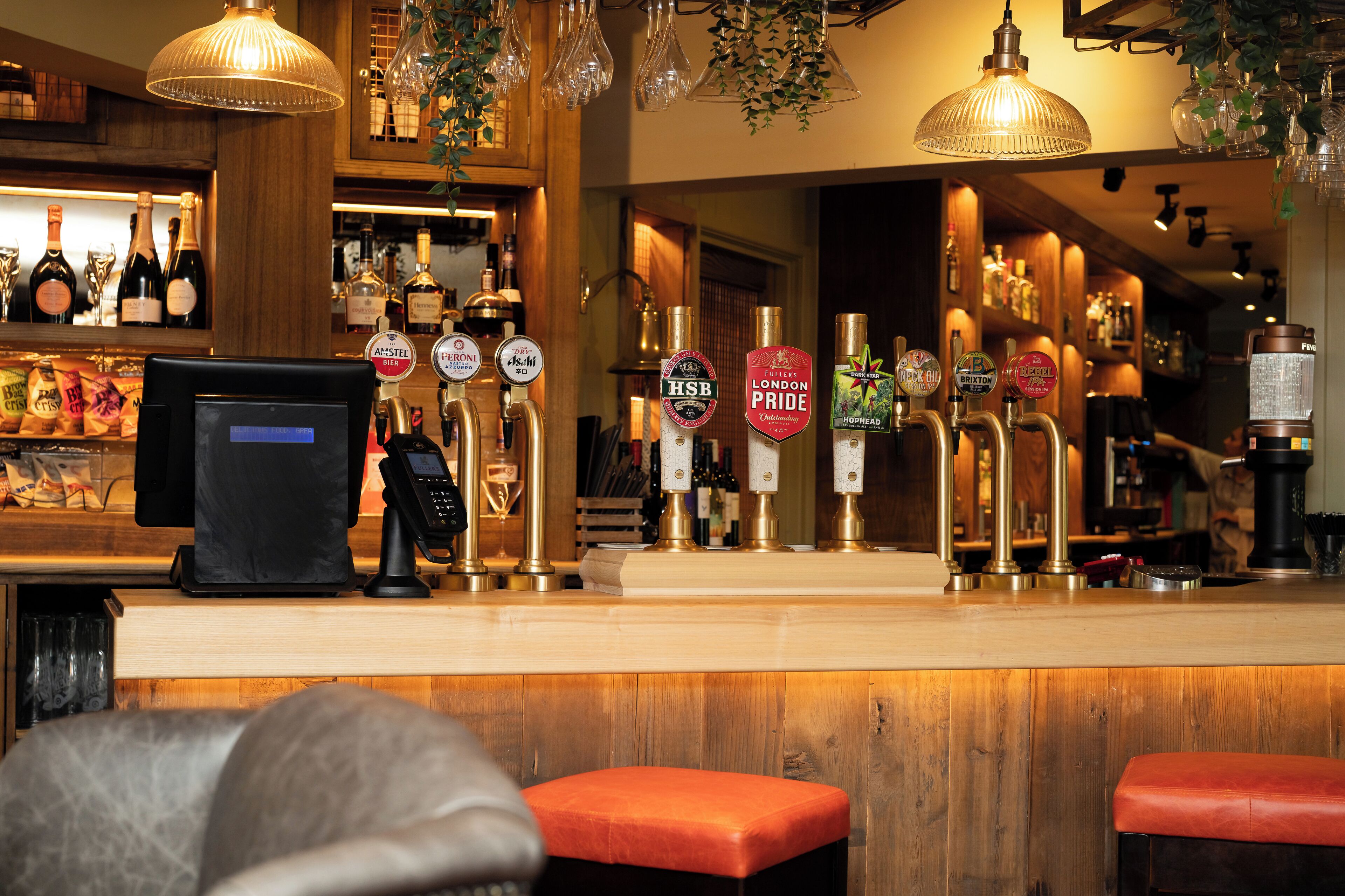 A bar area with multiple beer taps, a cash register, and a counter.