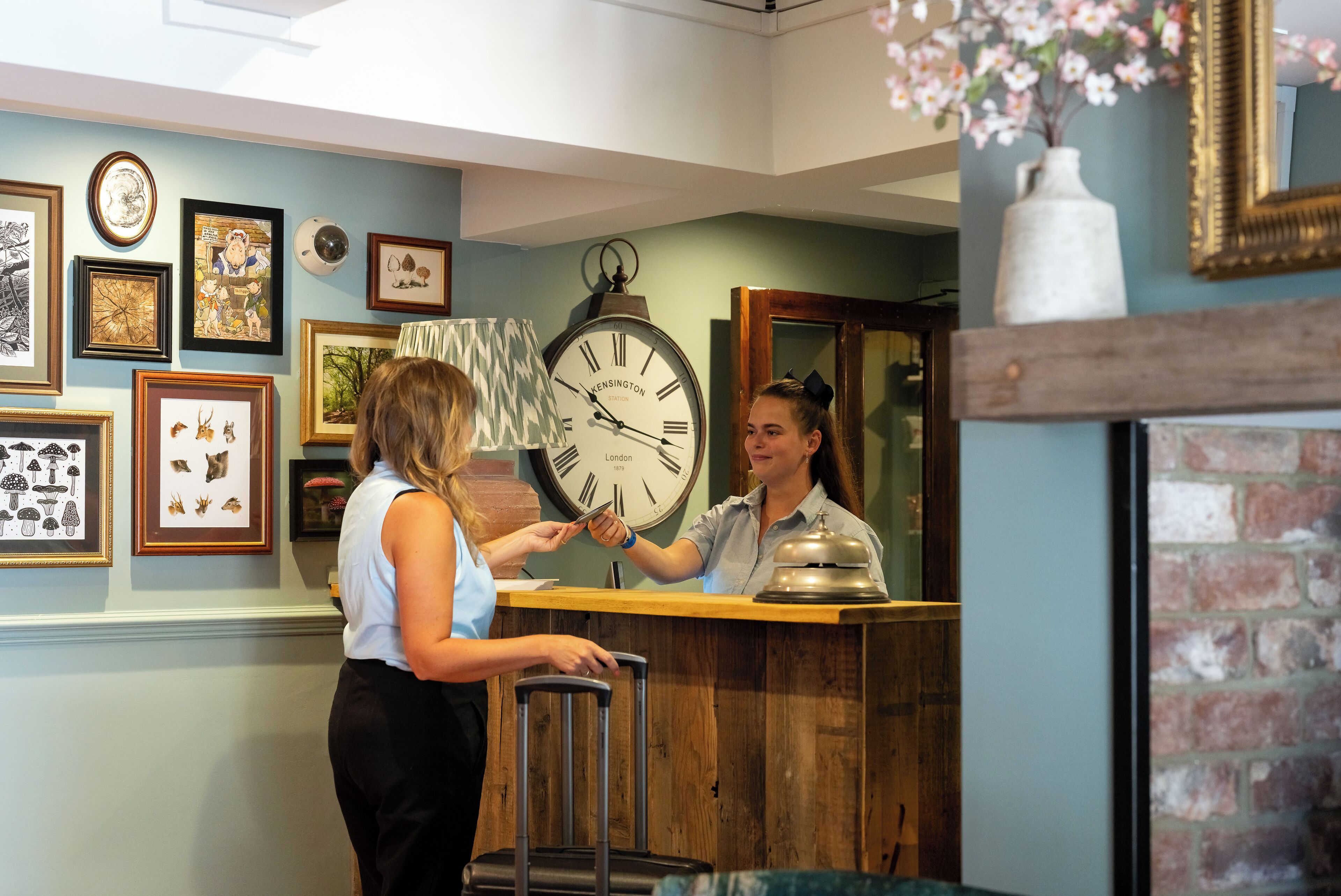 A reception area with a wooden counter, a clock, and various framed pictures on the wall.
