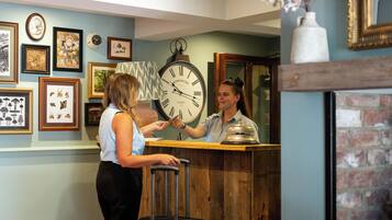 A reception area with a wooden counter, a clock, and various framed pictures on the wall.
