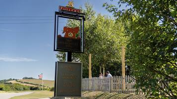 Tabella di segnaletica per The Hampshire Hog, che indica servizi come pub di campagna, ristorazione stagionale, spazi per eventi e camere da letto.