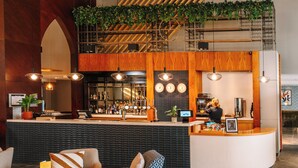 Un espace bar doté d’un comptoir en bois, de plusieurs luminaires suspendus et d’un comptoir d’accueil.