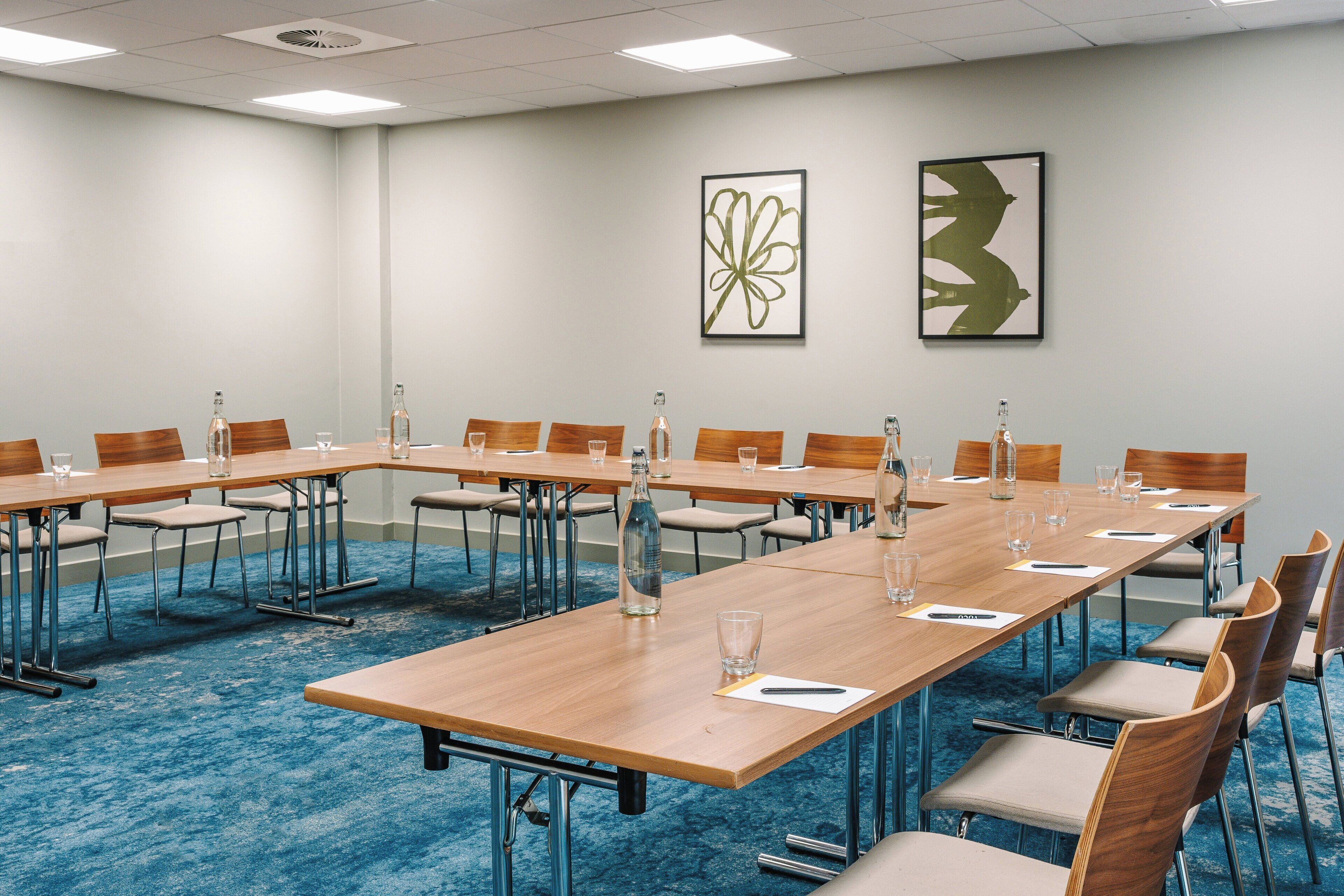 A conference room with long tables, chairs, and water bottles.