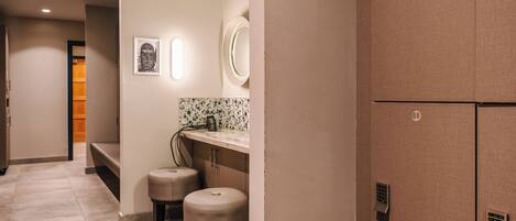 A hotel corridor with a seating area, a mirror, and a door leading to another room.