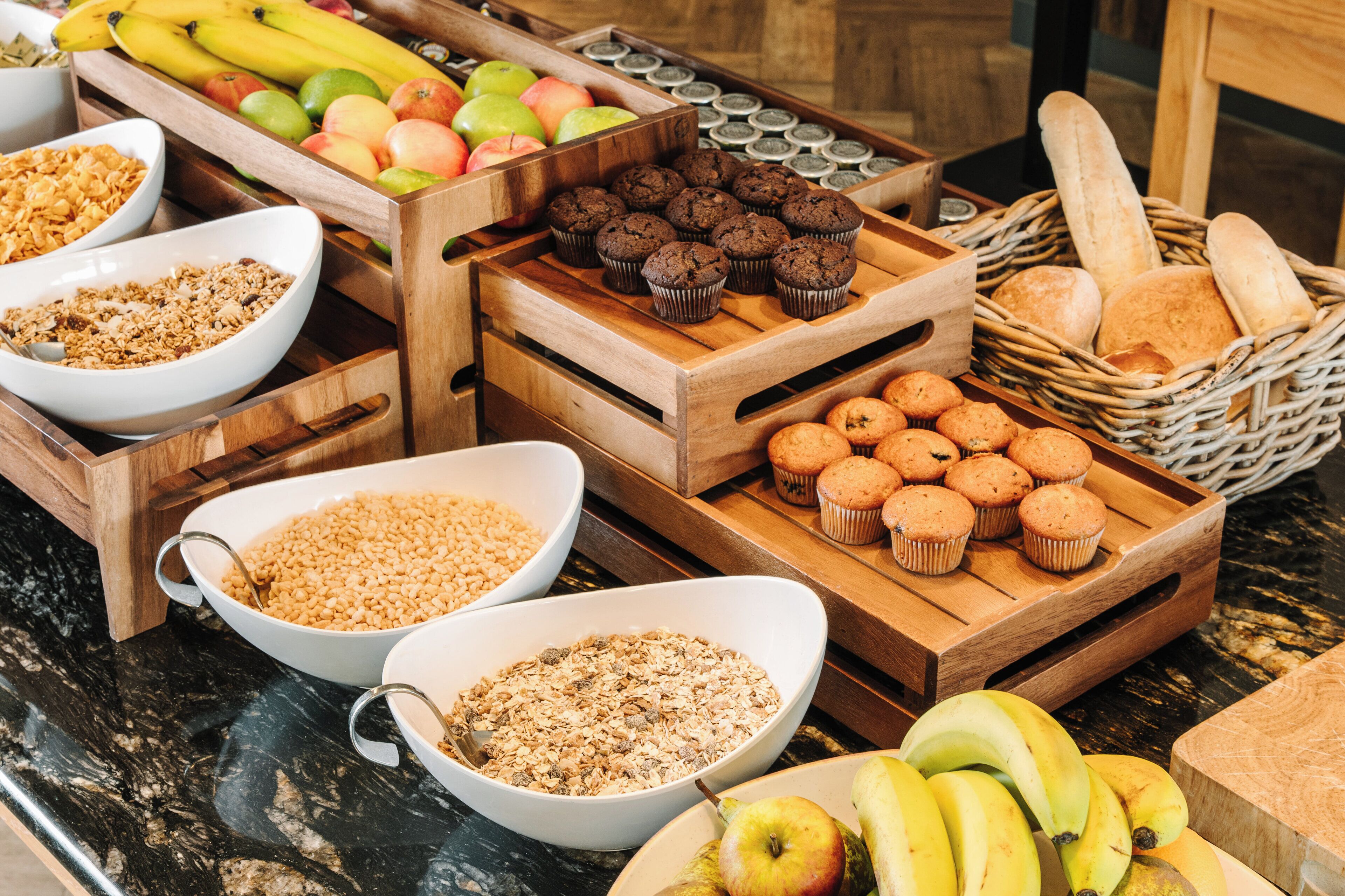 A breakfast buffet with various food items including fruits, muffins, and granola.