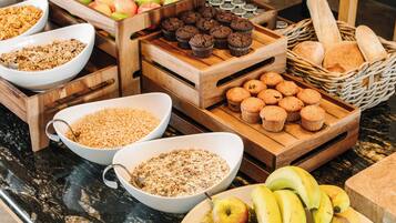 A breakfast buffet with various food items including fruits, muffins, and granola.
