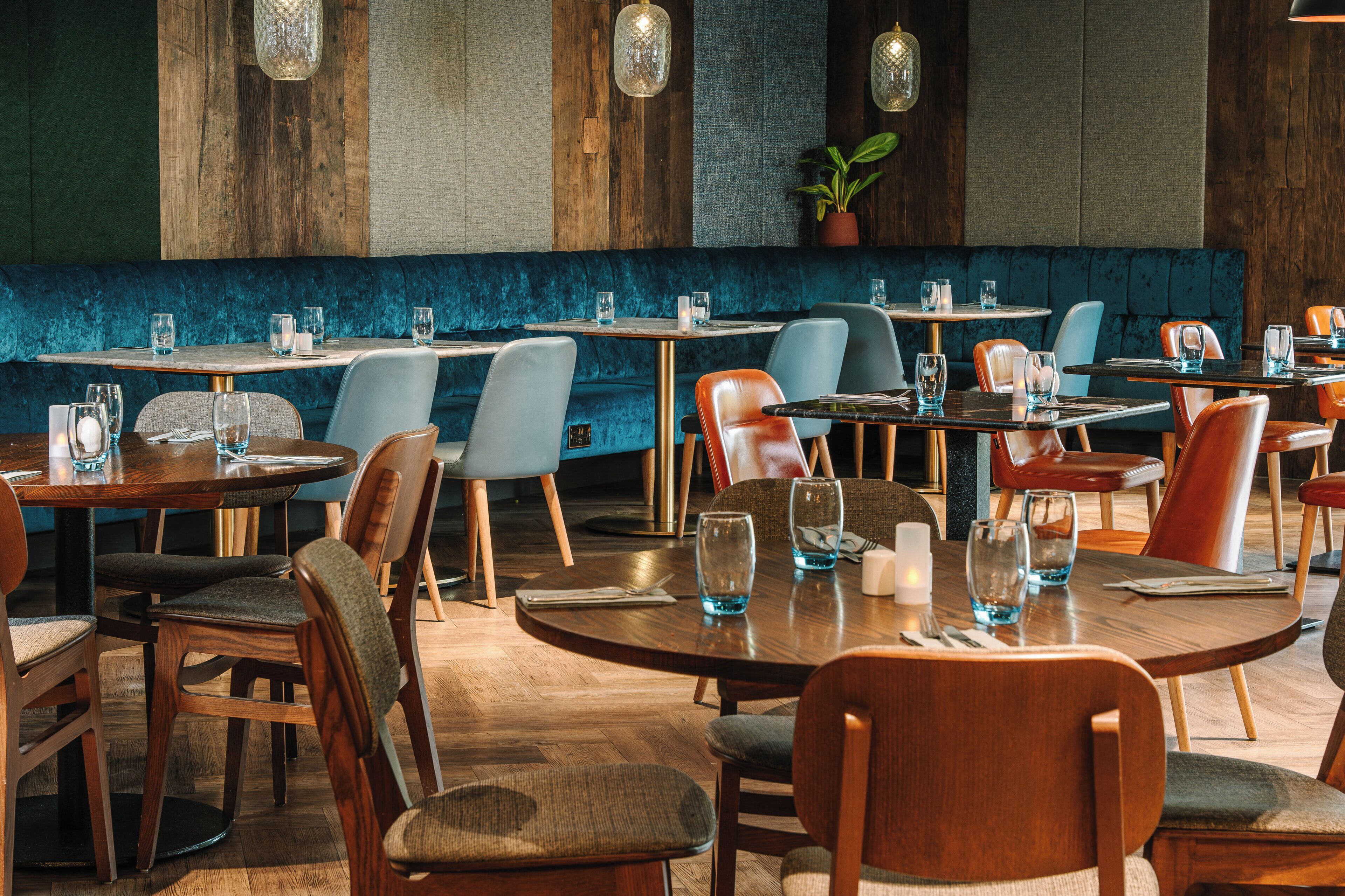 A restaurant interior with round tables, cushioned chairs, and wooden accents.