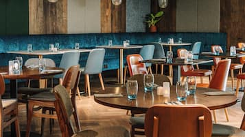 A restaurant interior with round tables, cushioned chairs, and wooden accents.
